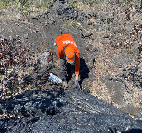 Color photograph of scientist taking a cold lava sample