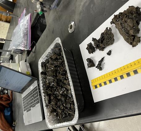 Color photograph of lava samples being prepped in a lab next to a laptop