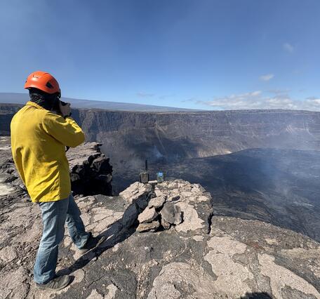 Color photograph of scientist on rim of caldera