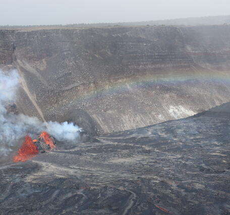 Color photograph of rainbow over erupting vents and lava lake