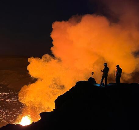 Color photograph of scientists monitoring eruption site