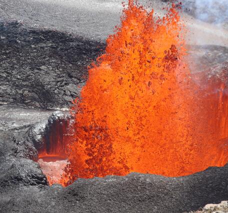 Molten lava fountain erupting from a vent of dark cooled lava
