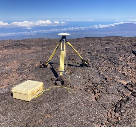 Color photograph of tripod on lava flow with mountain in the background