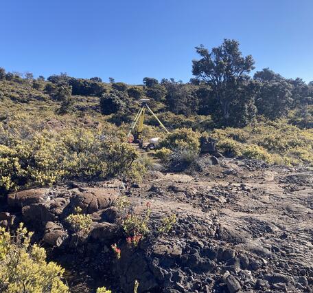 Color photograph of tripod on vegetated lava flow