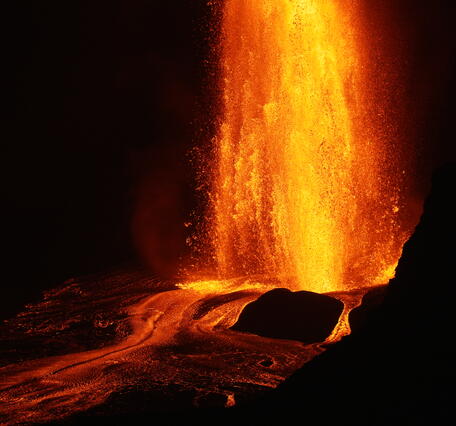 Color photograph of a lava fountain erupting at night