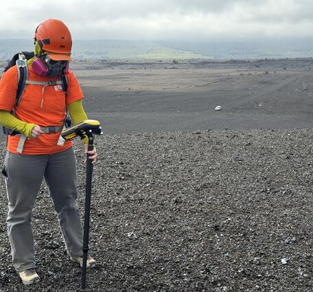 Color photograph of a scientist measuring a new volcanic deposit