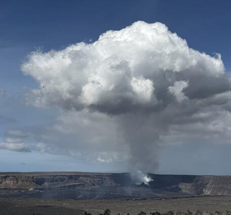 Color photograph of volcanic crater with degassing plume rising above it