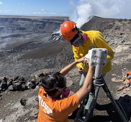 Color photograph of scientists servicing volcano monitoring camera
