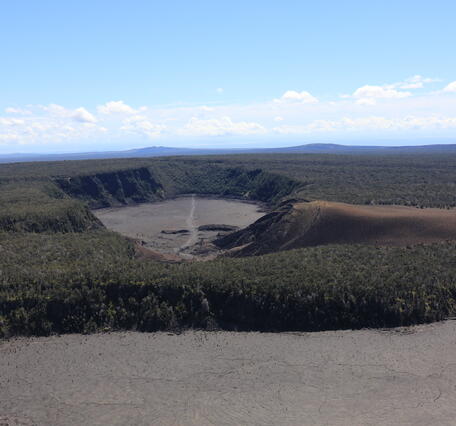 color photo looking toward an old eruption site from the 1980s with a clear hiking trail across it worn by visitors. 
