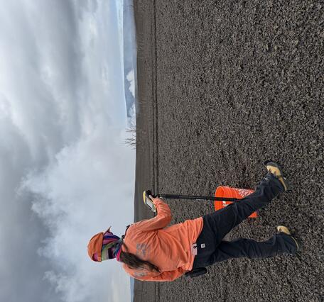 Color photograph of scientist taking measurement on volcanic landscape