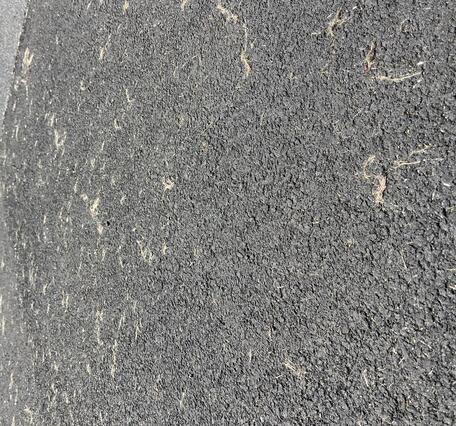 Color photograph of fine particles of volcanic glass on a paved road
