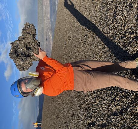 Color photograph of scientist holding recently erupted volcanic rock