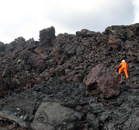 Color photograph of scientist on lava flow
