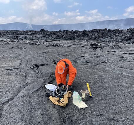 Color photograph of scientist assembling gear on lava flows located on crater floor