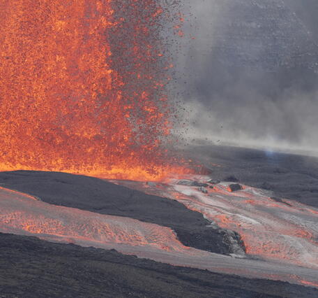 Color photograph of lava fountain base and lava flowing in channel