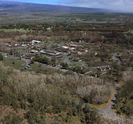 Color photograph of military camp surrounded by forrest and volcano