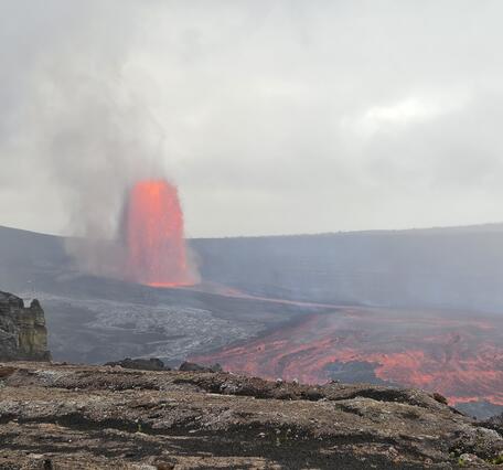 Color photograph of lava fountain and lava flow in crater