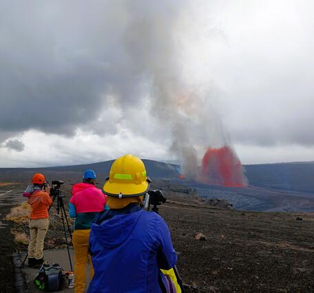 Color photograph of scientists observing volcanic eruption