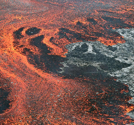 Color photograph of active lava flow on top of inactive lava flow