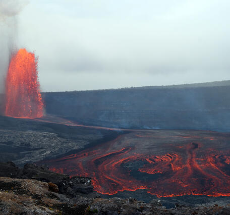 Color photograph of lava fountain and lava flow with crater