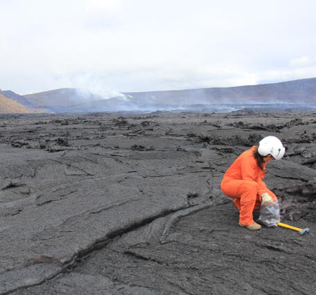 Color photograph of scientist collecting lava sample
