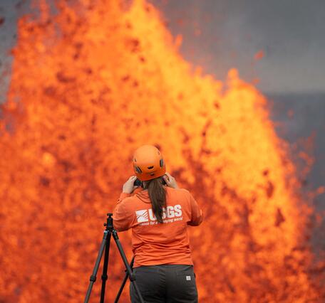 Color photograph of lava fountain with scientists in the foreground