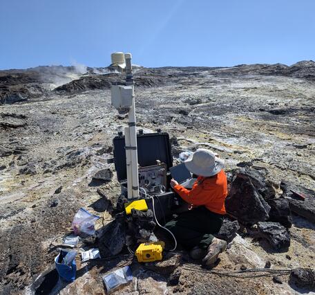 Color photograph of scientist working on volcanic gas monitoring instrumentation