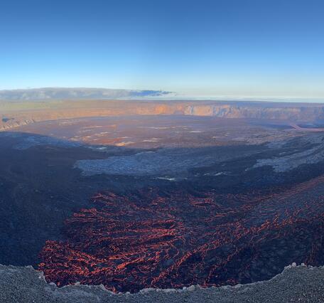 Color panoramic photo of volcanic crater with lava fountain and flows