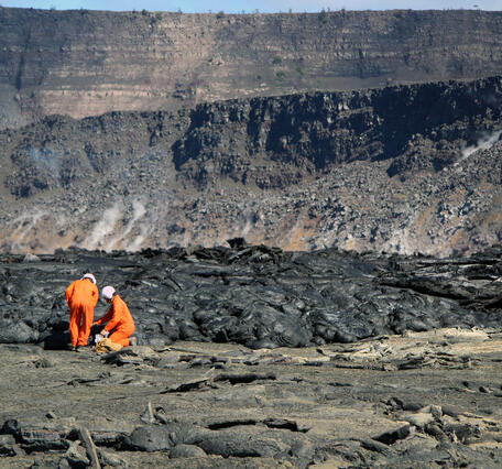 Color photograph of scientists collecting sample on crater floor