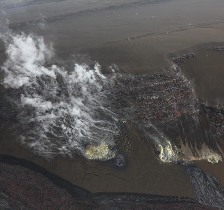 Color photograph of steaming volcanic vents on crater wall