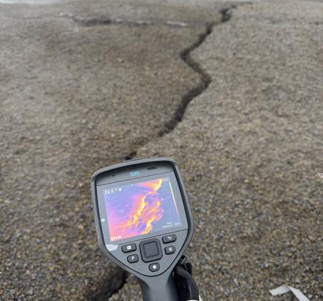 Color photograph of thermal camera showing temperature of ground crack