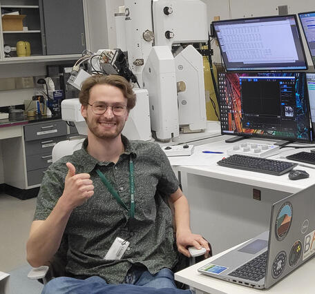 Nicholas E Powell gives a thumbs up while proudly showing off lab equipment