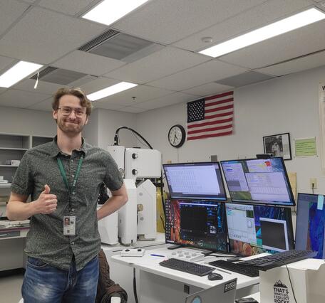 Nicholas E Powell gives a thumbs up while proudly showing off new lab equipment