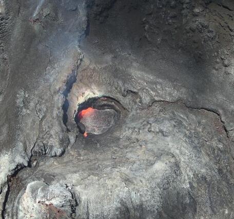 Color photo looking inside the north vent of the Halema‘uma‘u crater with lava visible in the vent. 