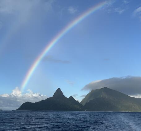 Color photo of a rainbow over the ocean.