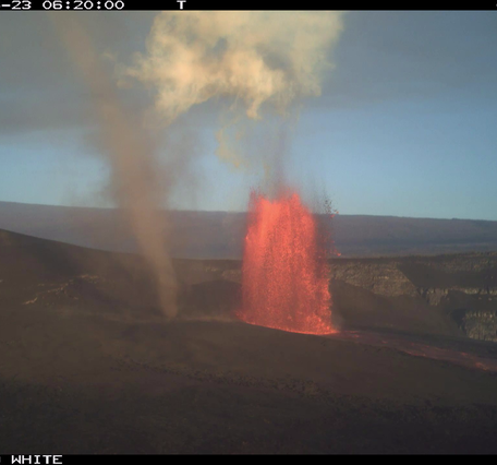 Color photograph of lava fountain during daylight with a dust devil nearby