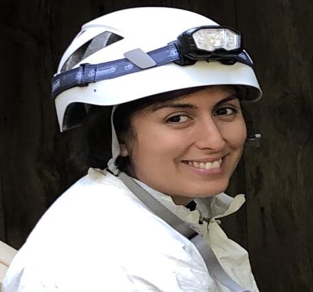 Ariel Leon wearing a white helmet with a head lamp and a white tyvek suit.