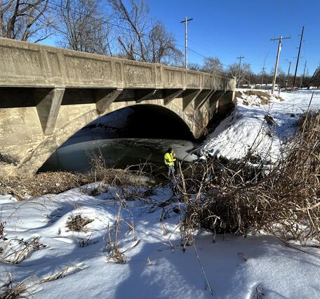 Scientists conducting discharge measurement in middle of stream during winter