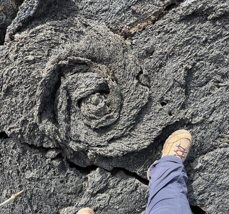 Color photograph of feature in lava flow with foot for scale