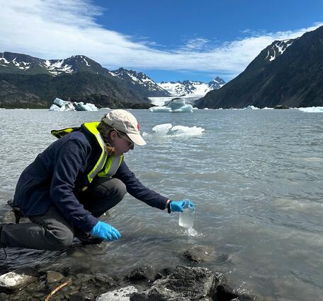 Scientist takes a water sample from a glacial lake in Alaska