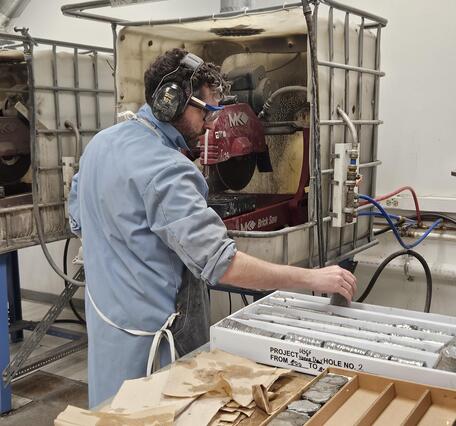 Scientist cuts a rock core with a saw and places into boxes
