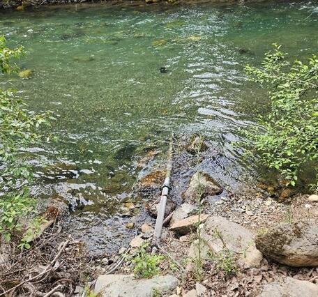 A pipe lays in a blue-green river.