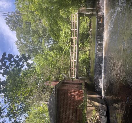 Looking upstream at a footbridge over a river next to a brock house