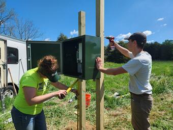 Two USGS scientists work on installing a monitoring box.