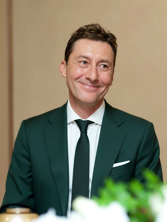 A headshot of a smiling man in a suit