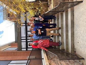 a group of people standing in a front of a building smiling for the camera