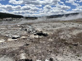 Barren, steaming ground with a water-filled crack trending away from the photographer