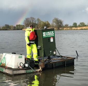 A biologist stands on a fully constructed bait delivery platform floating on water.