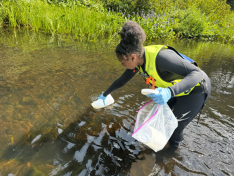 A researcher stands in a stream collected water samples.