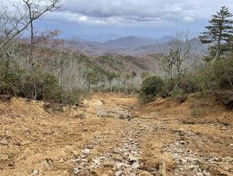 person stands on a hillslope covered with mud and rocks